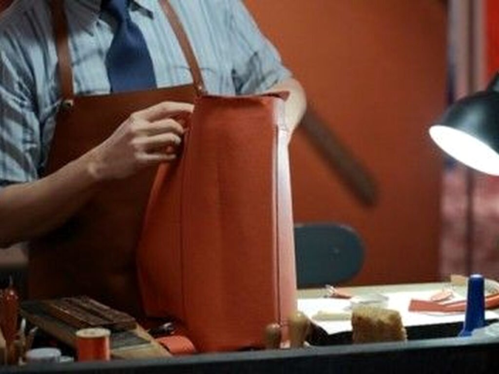 Artisan handcrafting leather bag details